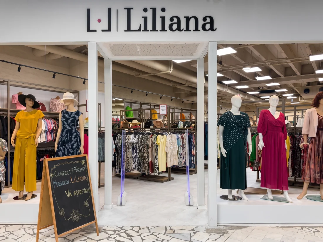 Vitrina magazinului Liliana Trade, cu firma montată deasupra intrării și manechinele din față